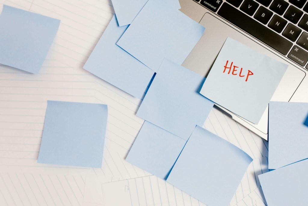 A cluttered workspace with sticky notes covering a laptop, with one note reading "HELP," symbolizing academic stress and the need for organization. does adhd qualify for iep