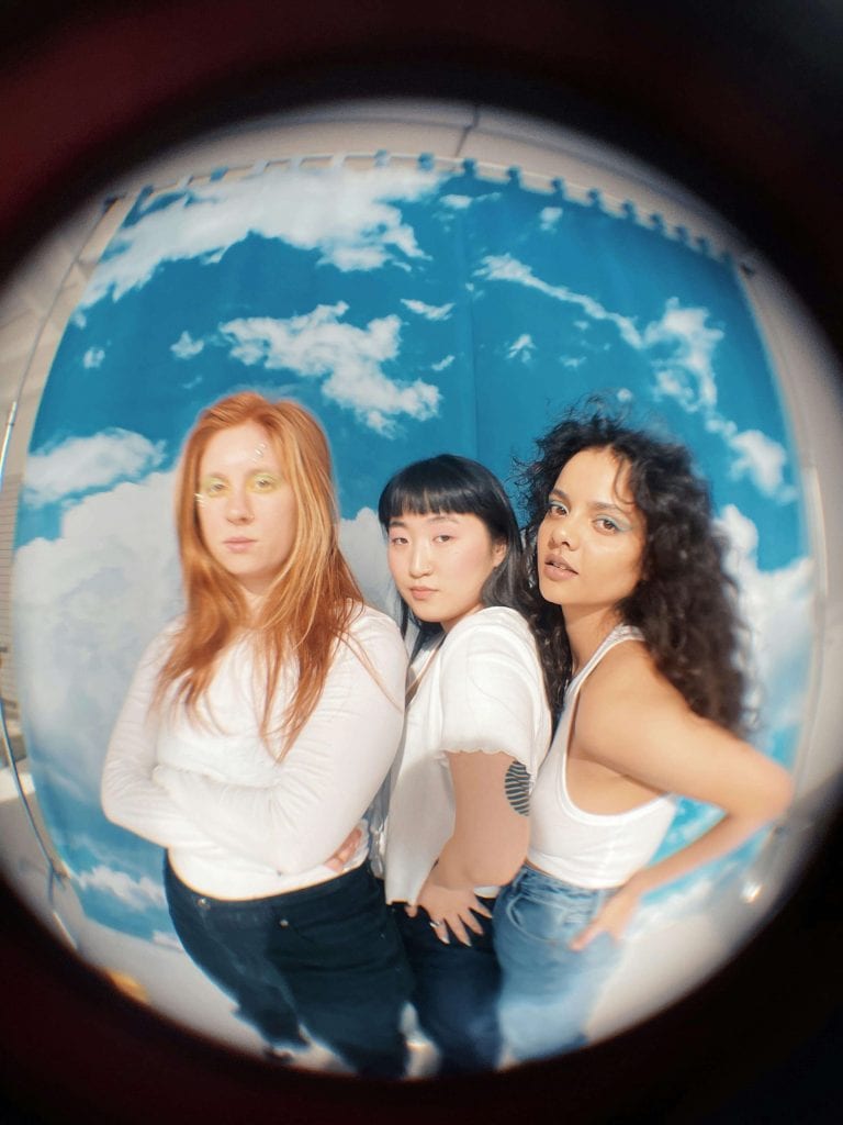 Three young women pose confidently against a cloud-filled backdrop, symbolizing self-awareness, individuality, and the diverse ways ADHD presents across genders.