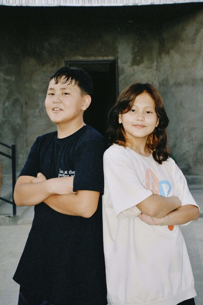 Two children stand back-to-back with arms crossed, representing confidence and resilience. ADHD can affect a child's self-perception, learning, and social interactions.