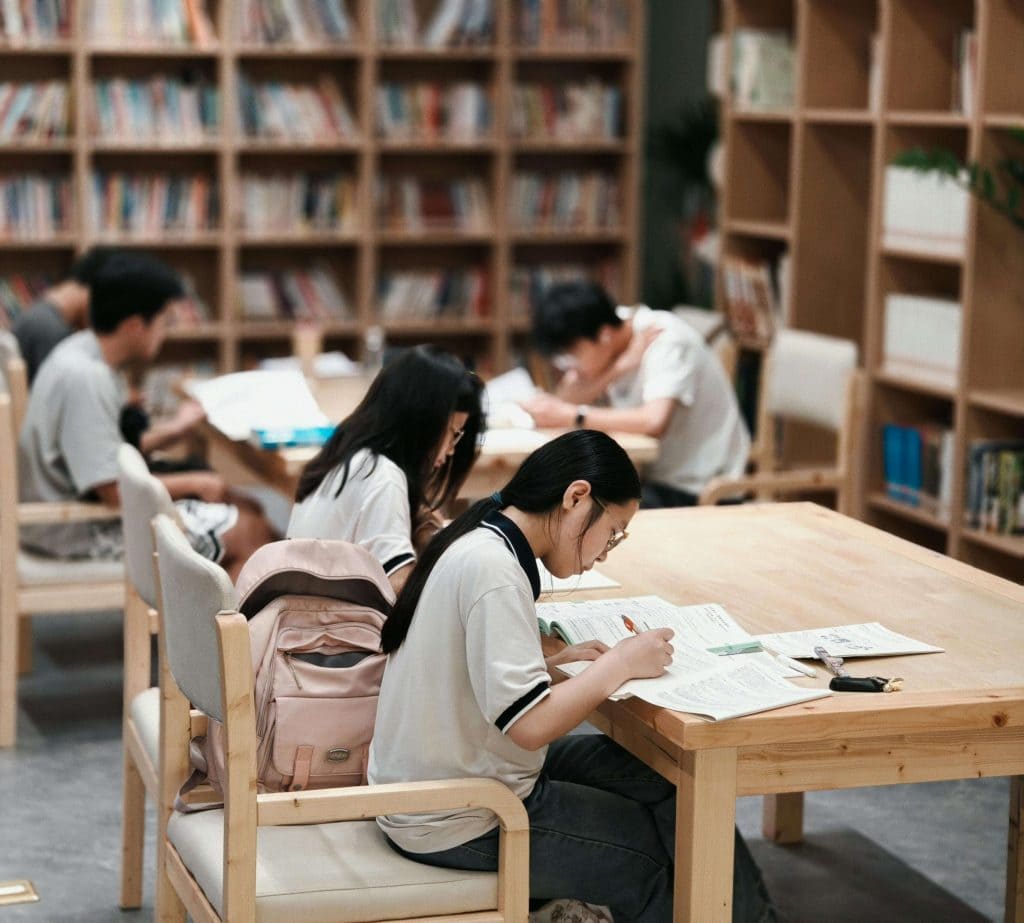 A group of students focused on their work in a school library. This calm, low-stimulation environment reflects one type of 504 accommodation that can support students with autism in staying regulated and engaged.