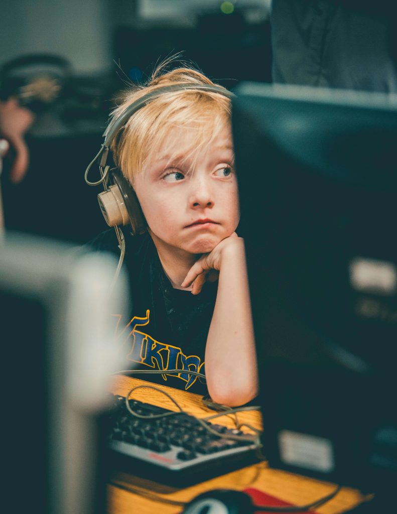 A young boy wearing headphones while sitting at a computer station. Sensory tools like headphones can be essential 504 accommodations for students with autism who are sensitive to noise or need help focusing.